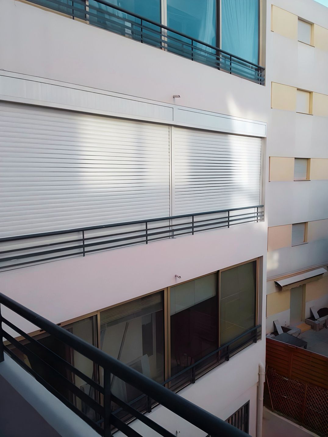 Volet roulant blanc sur une façade avec balcon
