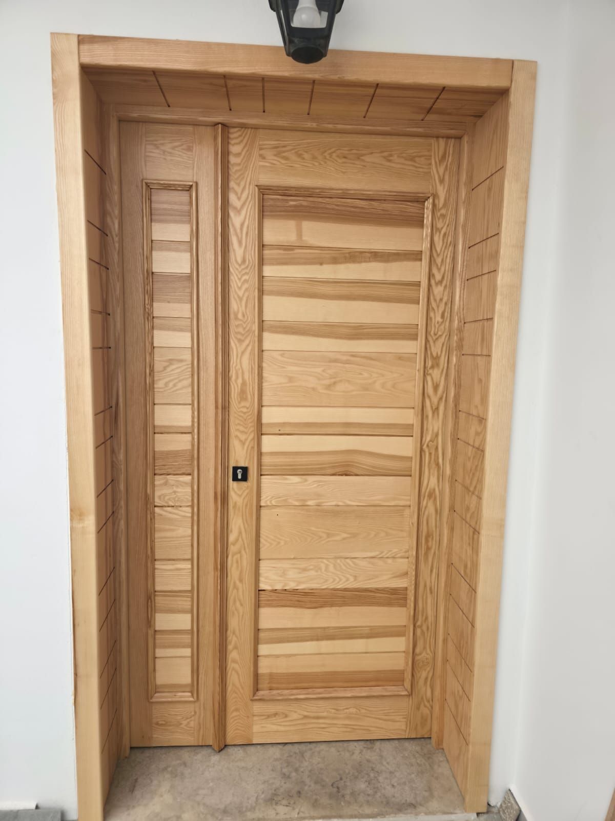 Porte d’entrée en bois naturel et encadrement sur mesure