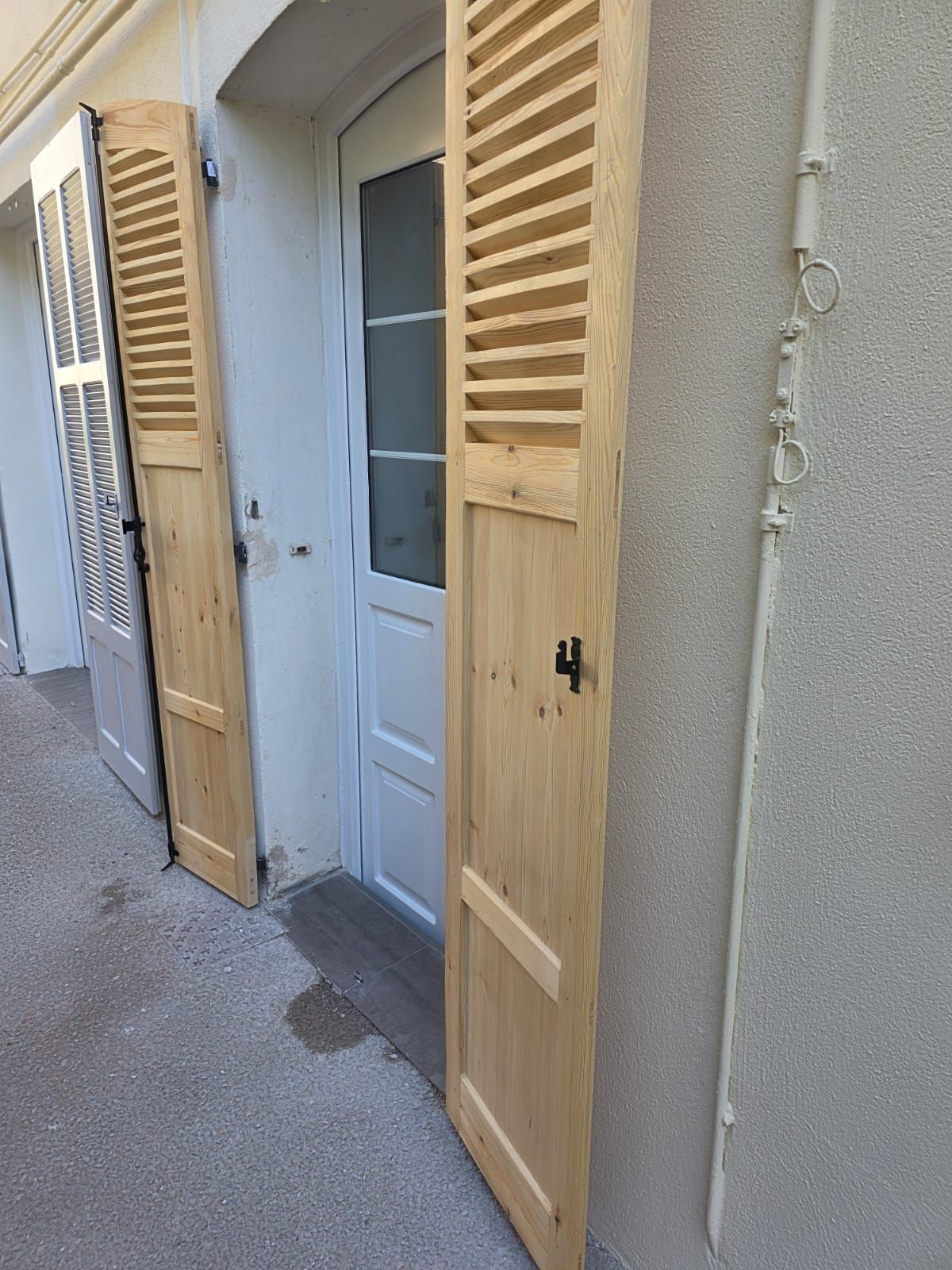 Persiennes bois ouvertes devant une entrée